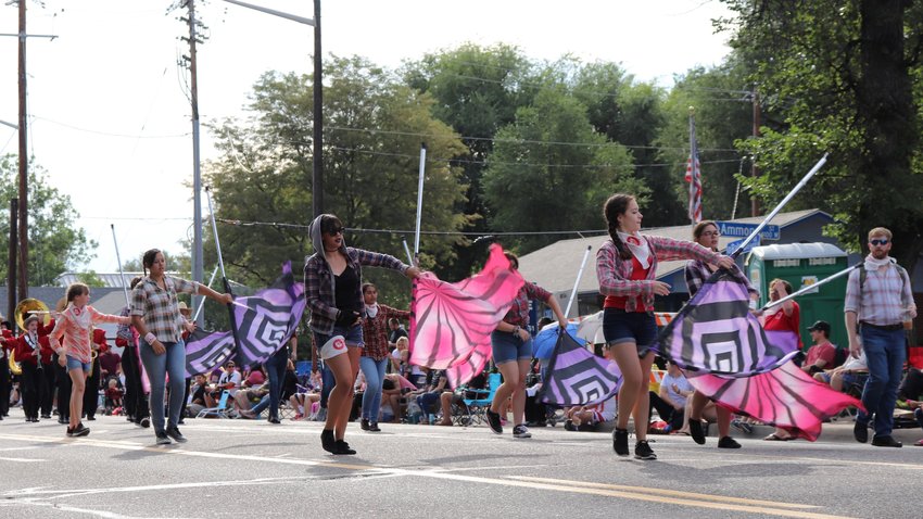 Arvada High School students twirl their flags as they lead in the high school's marching band.